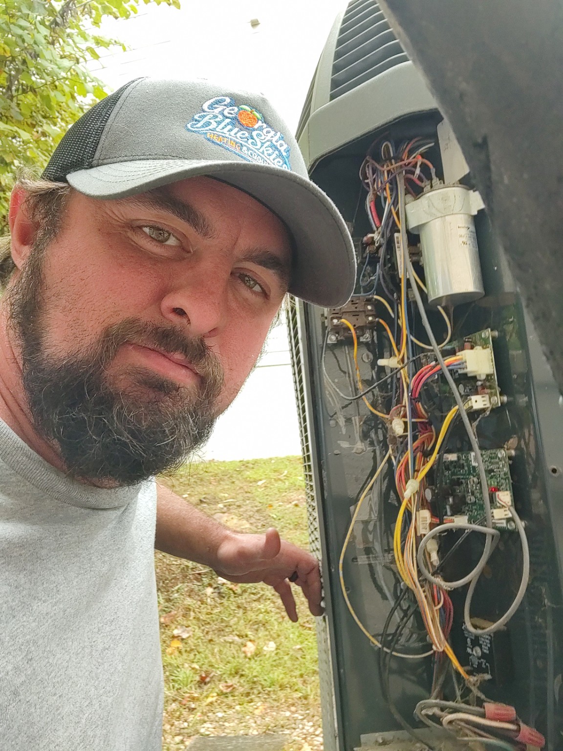 Derrick Turner, owner of Georgia Blue Skies Heating and Cooling, working beside an outdoor HVAC unit